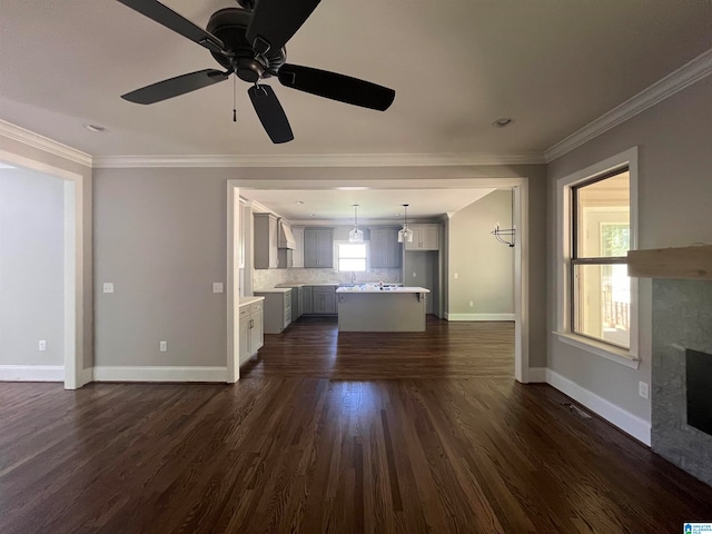 unfurnished living room featuring ceiling fan, dark wood-type flooring, and ornamental molding