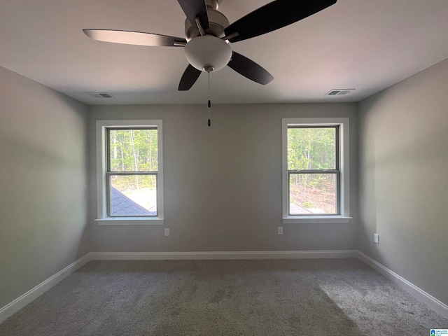 carpeted spare room featuring plenty of natural light and ceiling fan