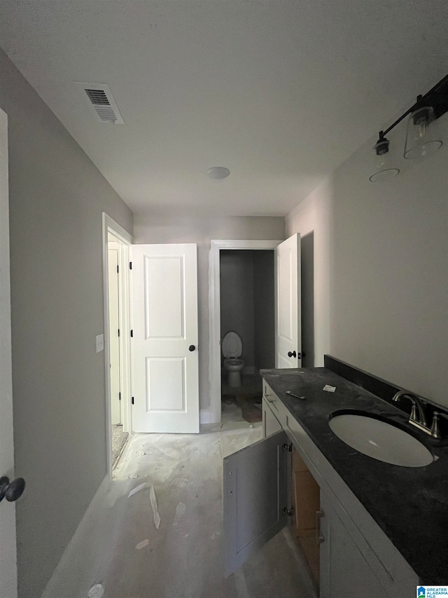 bathroom featuring vanity, toilet, and concrete flooring