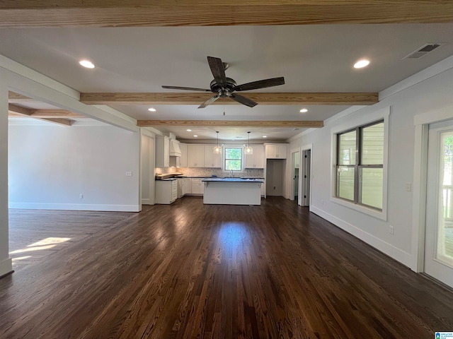 unfurnished living room with beamed ceiling, dark hardwood / wood-style flooring, and a wealth of natural light