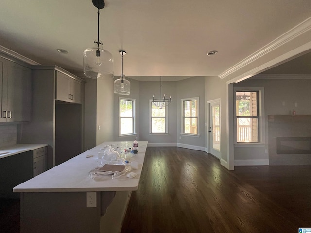 kitchen with dark hardwood / wood-style flooring, gray cabinetry, crown molding, pendant lighting, and a kitchen island