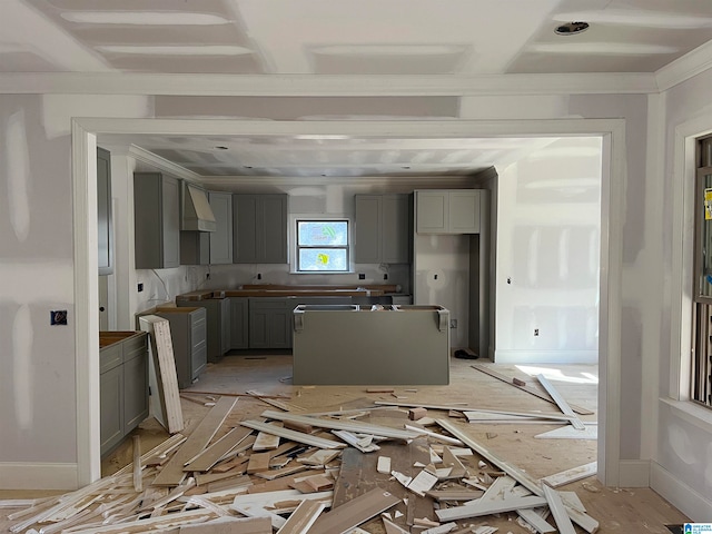 kitchen featuring light wood-type flooring, backsplash, wall chimney exhaust hood, gray cabinetry, and crown molding