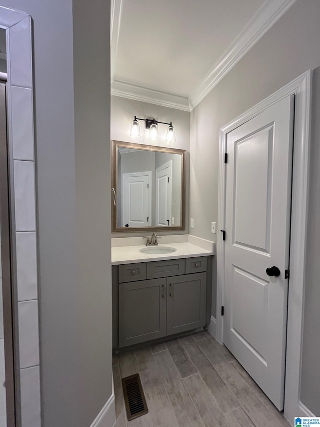 bathroom with hardwood / wood-style floors, vanity, and ornamental molding