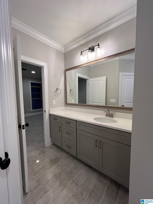 bathroom with crown molding, vanity, and hardwood / wood-style flooring