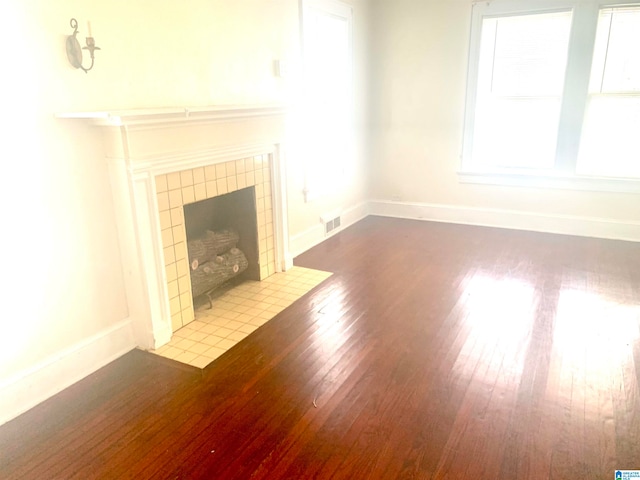 unfurnished living room featuring a fireplace, a wealth of natural light, and wood-type flooring