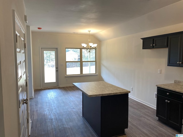 kitchen with a center island, lofted ceiling, dark wood-type flooring, hanging light fixtures, and a chandelier