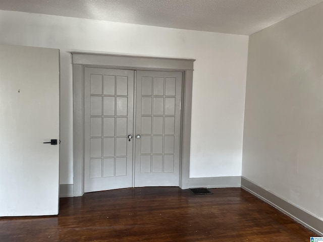 interior space with visible vents, baseboards, wood finished floors, and a textured ceiling