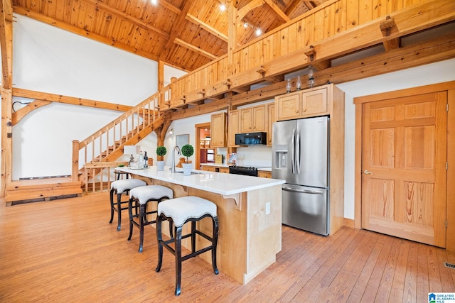 kitchen with light wood-type flooring, beamed ceiling, black appliances, and wooden ceiling