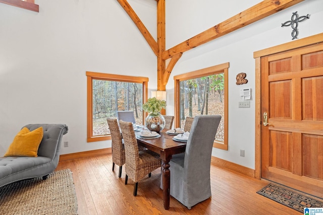 dining area with high vaulted ceiling, light hardwood / wood-style floors, and beamed ceiling