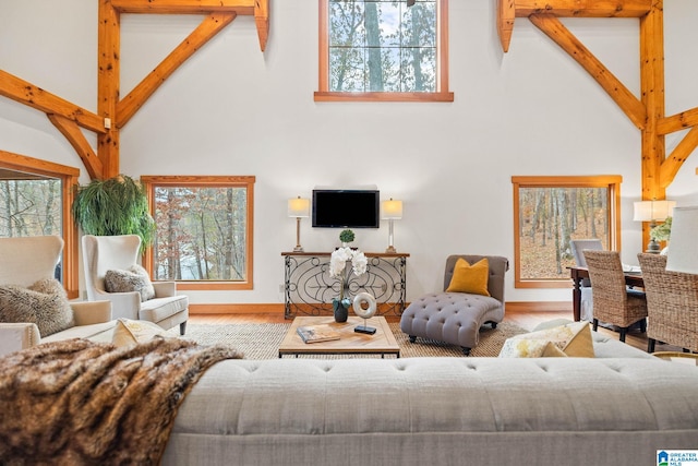 living room featuring light hardwood / wood-style flooring, beamed ceiling, and a high ceiling