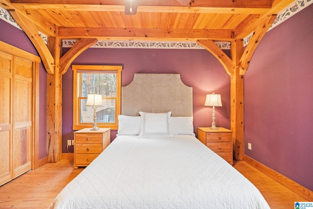 bedroom with a closet, wood ceiling, beamed ceiling, and light hardwood / wood-style flooring