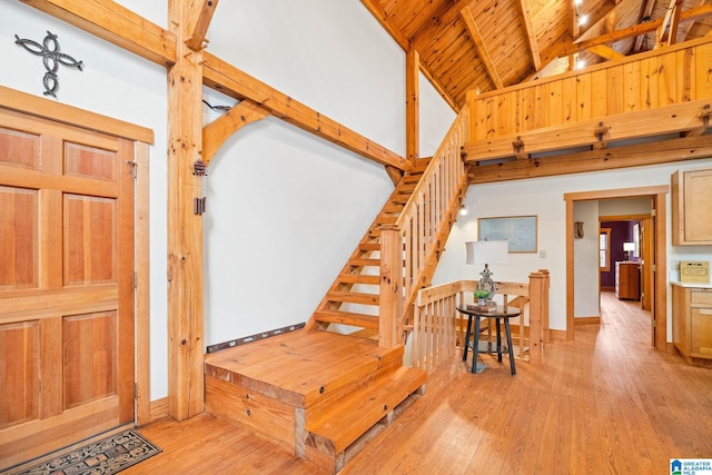 stairs featuring high vaulted ceiling, light hardwood / wood-style flooring, wood ceiling, and beamed ceiling