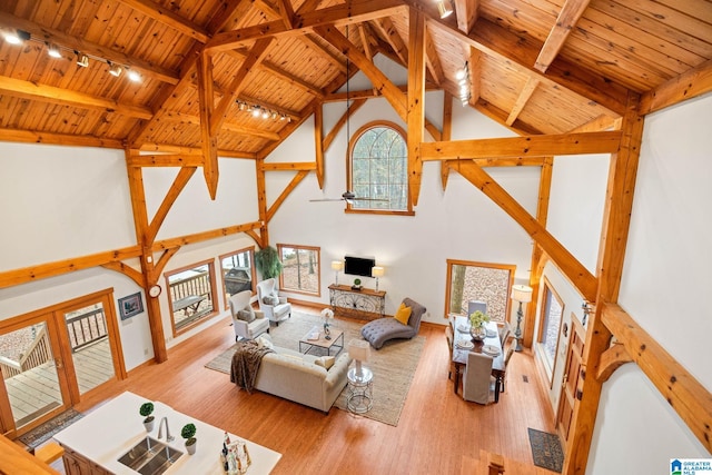 living room featuring track lighting, high vaulted ceiling, light wood-type flooring, beam ceiling, and wood ceiling