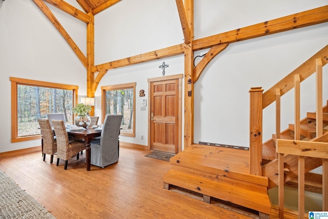 dining area featuring beamed ceiling, high vaulted ceiling, and light hardwood / wood-style floors