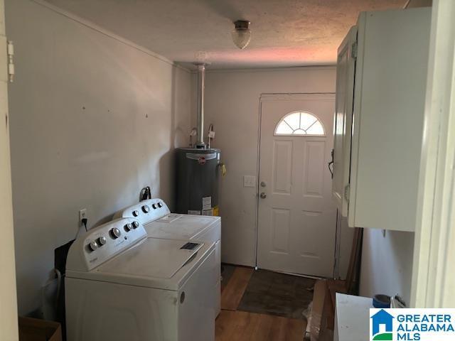 laundry room featuring water heater, cabinets, wood-type flooring, and washing machine and dryer