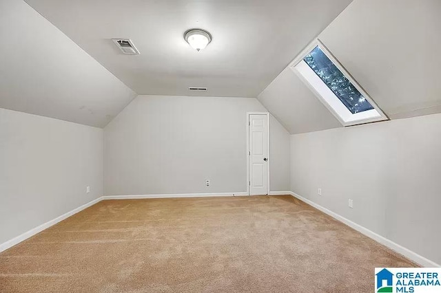 additional living space featuring lofted ceiling with skylight and light carpet