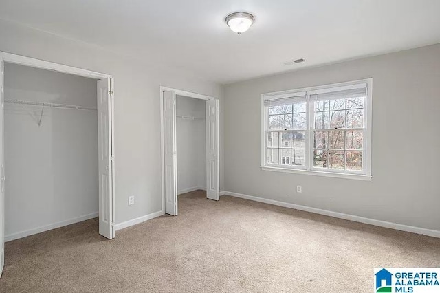 unfurnished bedroom with carpet and two closets