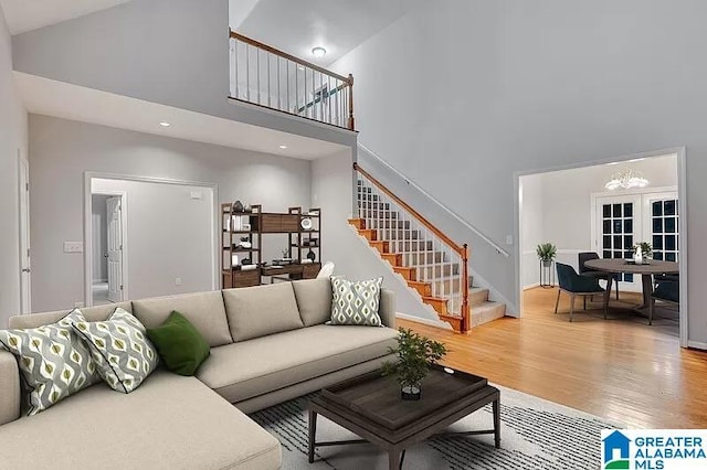 living room featuring wood-type flooring, high vaulted ceiling, and french doors