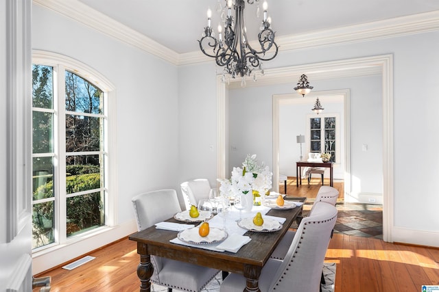 dining area with ornamental molding, light hardwood / wood-style floors, and a notable chandelier