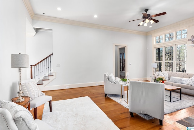 living room with light hardwood / wood-style flooring, ceiling fan, and crown molding