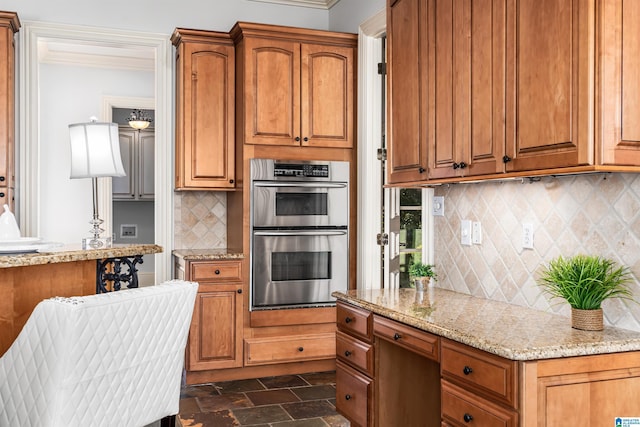 kitchen with light stone countertops, double oven, and tasteful backsplash