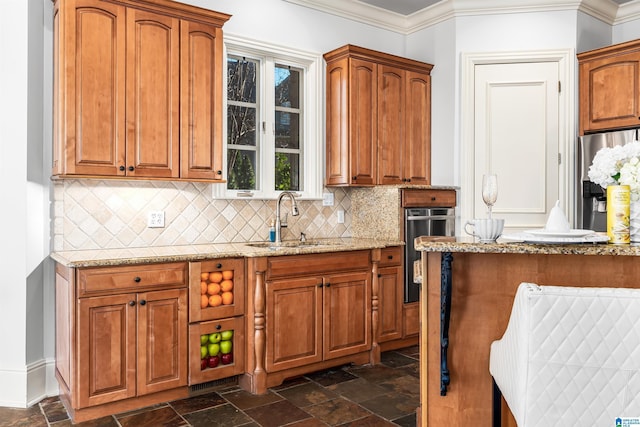 kitchen with sink, light stone counters, stainless steel refrigerator with ice dispenser, decorative backsplash, and ornamental molding