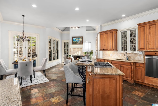 kitchen featuring tasteful backsplash, stainless steel appliances, sink, decorative light fixtures, and a kitchen island