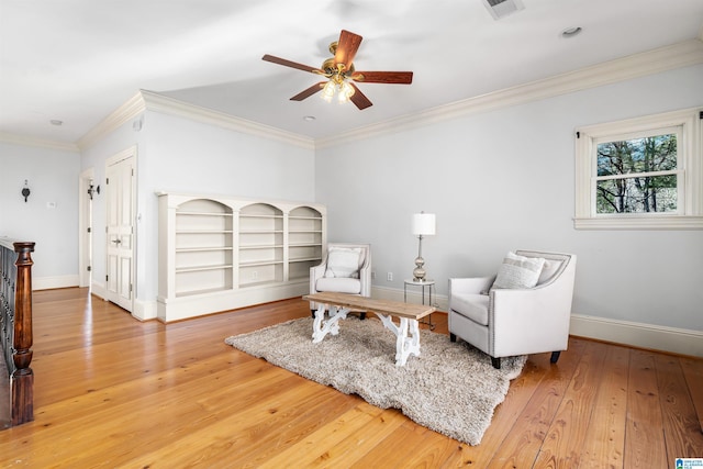 living area featuring hardwood / wood-style floors, ceiling fan, and crown molding