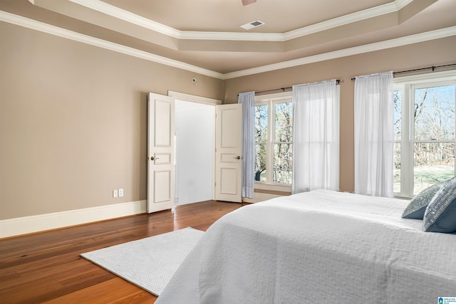 bedroom featuring wood-type flooring, a tray ceiling, and ornamental molding