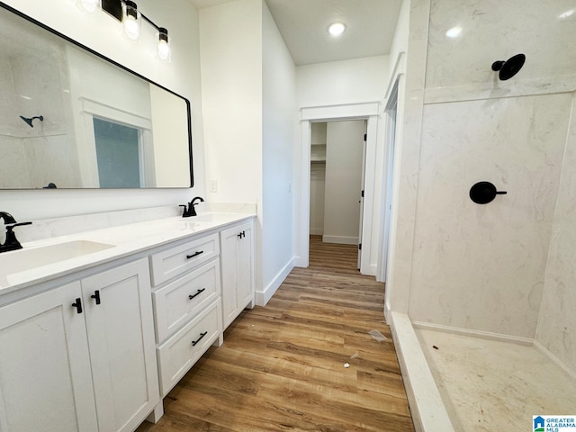 bathroom featuring wood-type flooring, a tile shower, and vanity