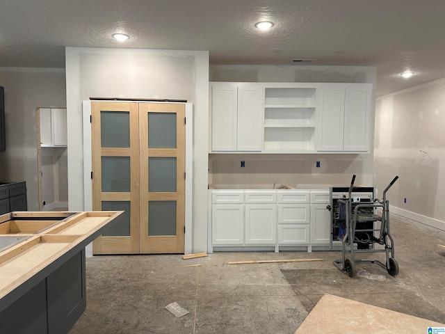 kitchen featuring a textured ceiling and white cabinets