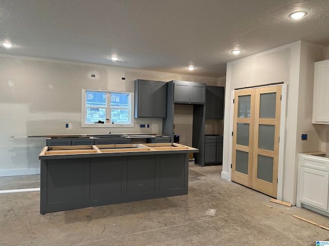 kitchen with white cabinetry, a center island, a textured ceiling, and gray cabinetry