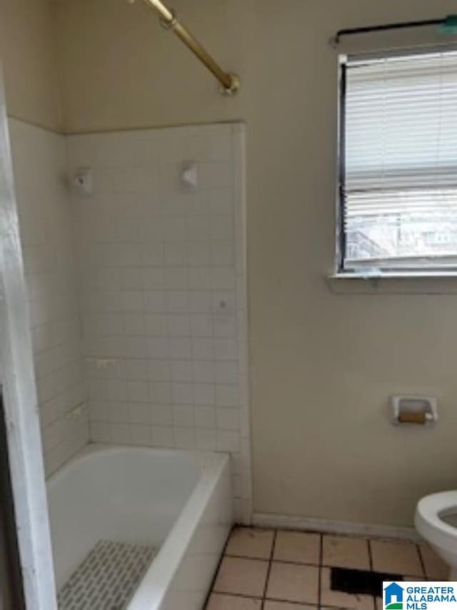 bathroom with tiled shower / bath combo, tile patterned floors, and toilet