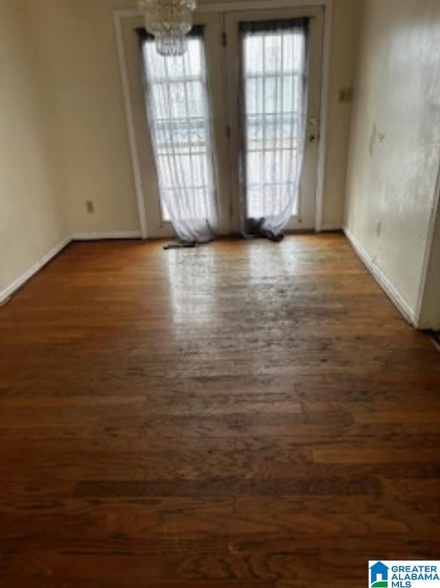 unfurnished room featuring a notable chandelier, dark hardwood / wood-style flooring, and plenty of natural light