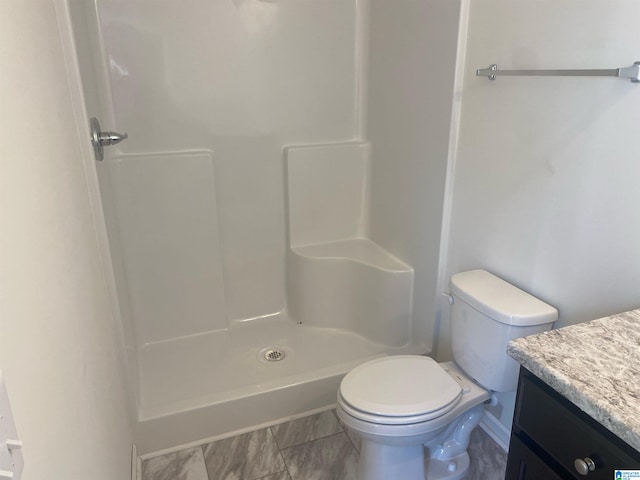 bathroom featuring toilet, a shower, and vanity