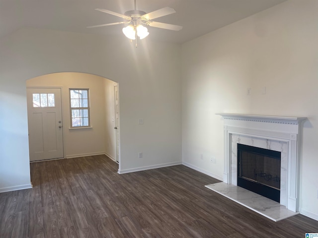 unfurnished living room featuring a ceiling fan, a high end fireplace, dark wood finished floors, and baseboards