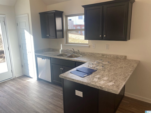 kitchen featuring baseboards, dishwasher, a sink, light countertops, and wood finished floors