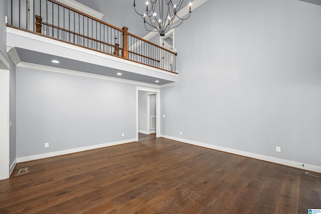 unfurnished living room with wood-type flooring, a high ceiling, and a chandelier