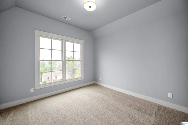 carpeted empty room featuring lofted ceiling