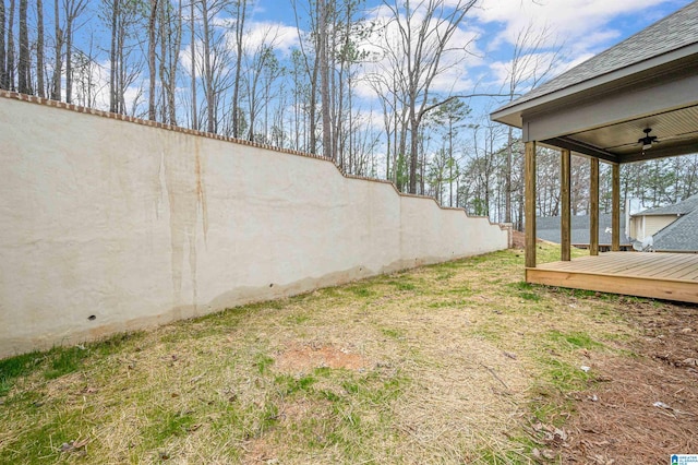 view of yard with a deck and ceiling fan