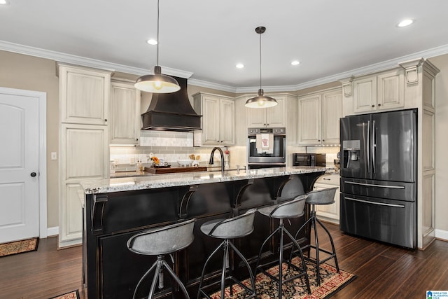 kitchen with cream cabinetry, light stone counters, stainless steel appliances, and hanging light fixtures