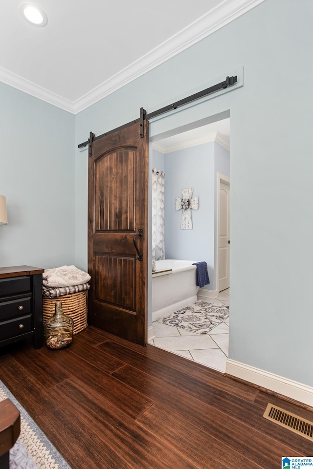 bedroom with a barn door, light hardwood / wood-style floors, and crown molding