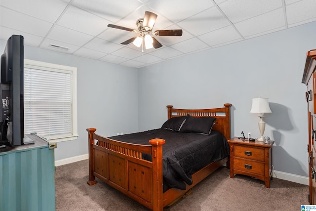 carpeted bedroom featuring ceiling fan and a drop ceiling