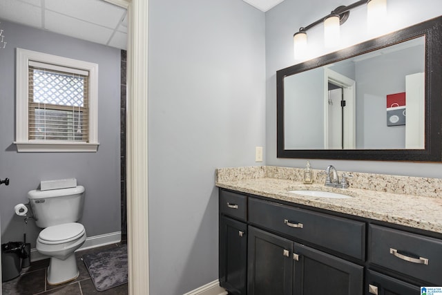 bathroom featuring tile patterned flooring, a drop ceiling, vanity, and toilet