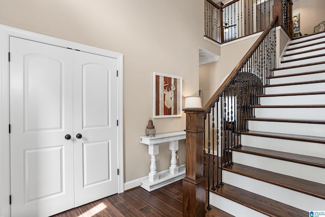 staircase with hardwood / wood-style floors and a high ceiling