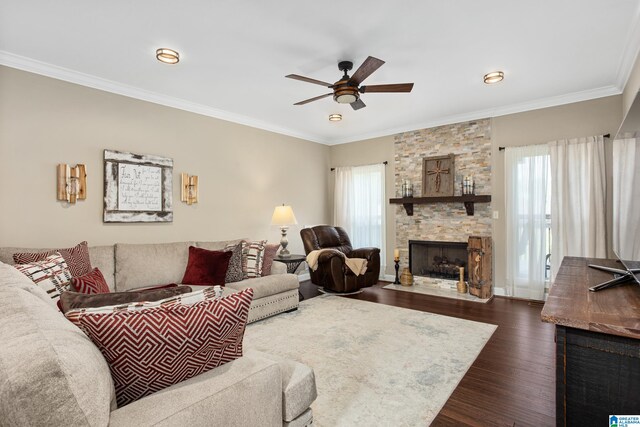 living room featuring dark hardwood / wood-style flooring, a stone fireplace, a healthy amount of sunlight, and crown molding