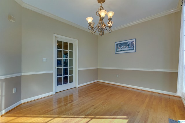 empty room featuring wood-type flooring, crown molding, and a notable chandelier