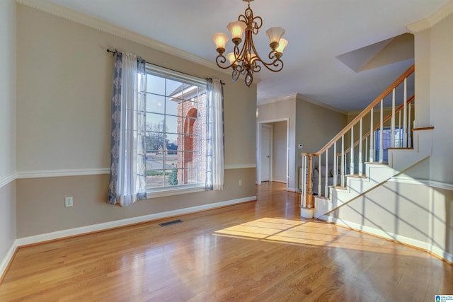 foyer with a chandelier, wood-type flooring, and ornamental molding