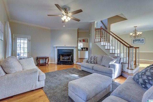 living room with hardwood / wood-style floors, ceiling fan with notable chandelier, and ornamental molding