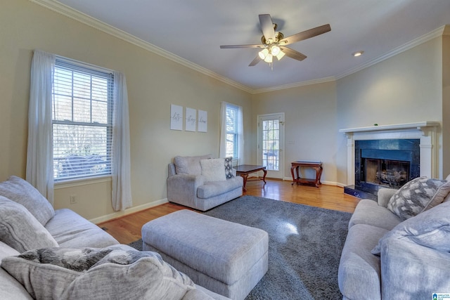 living room with ceiling fan, light hardwood / wood-style floors, ornamental molding, and a tiled fireplace